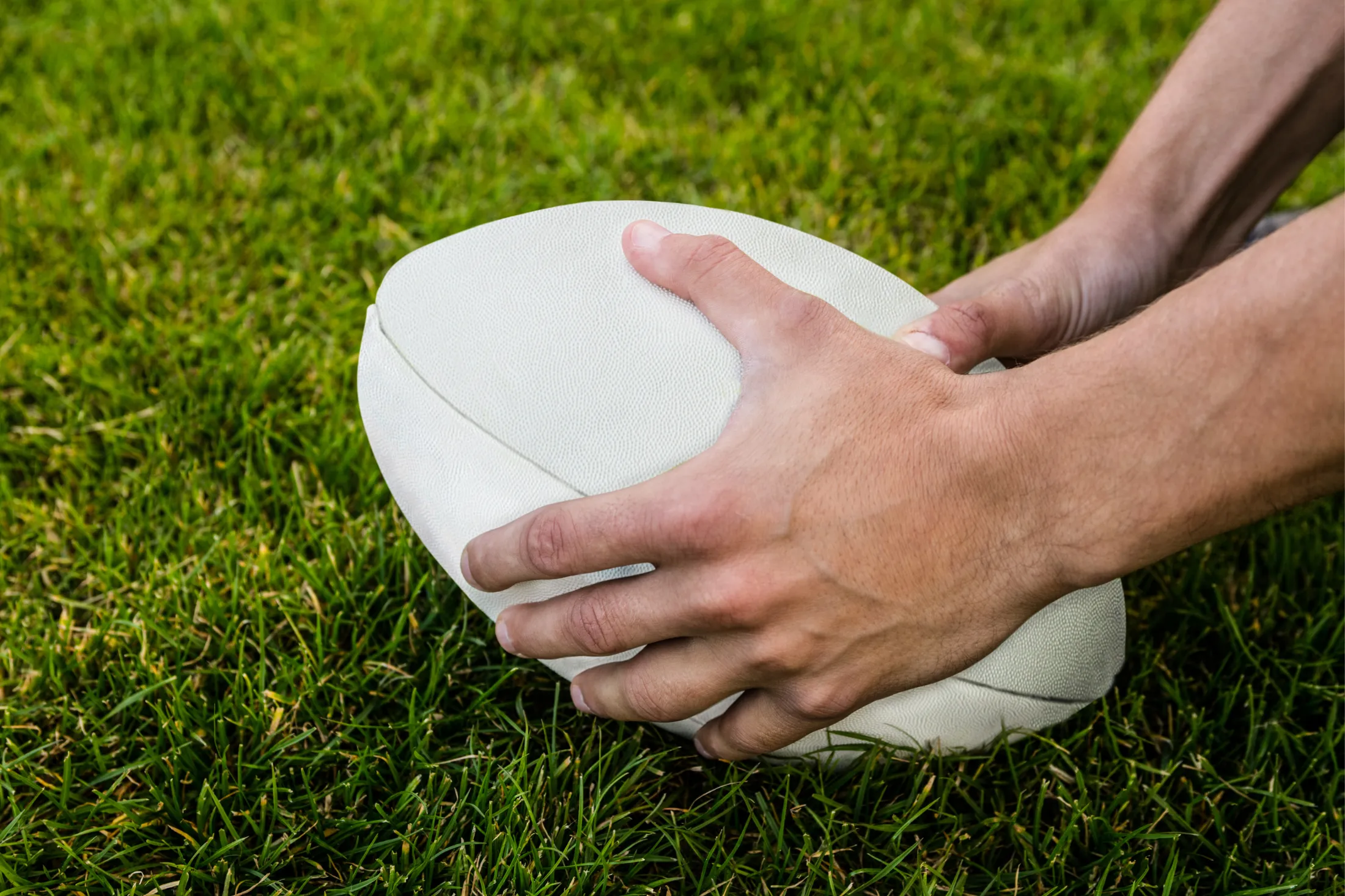 A rugby ball being placed on a stadium field