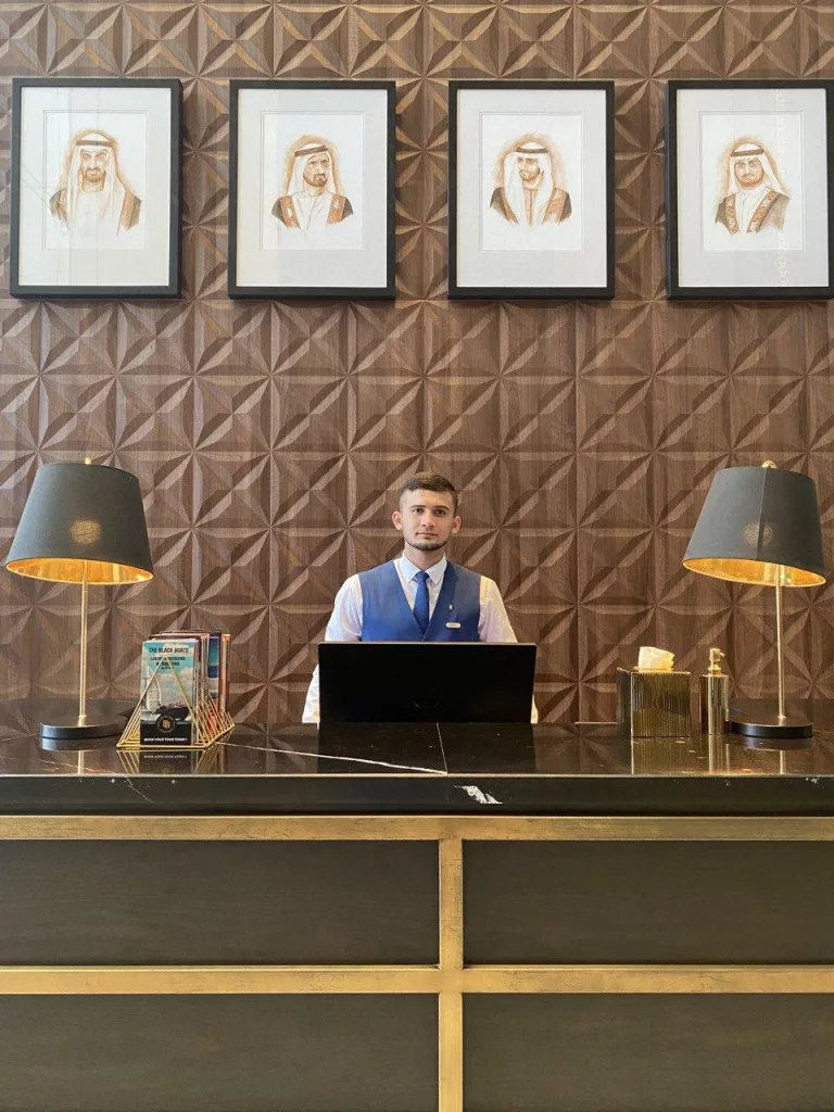 A nicely groomed man standing in a hotel uniform at reception of the Hotel in Dubai